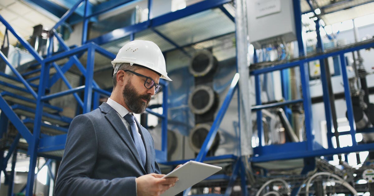 A chief Engineer in the hard hat walks through industrial factory.
