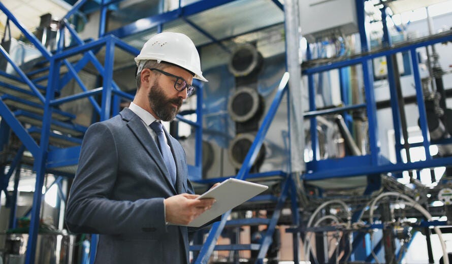 A chief Engineer in the hard hat walks through industrial factory