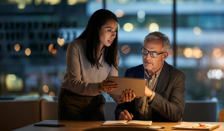 A woman standing beside a seated man in a modern office