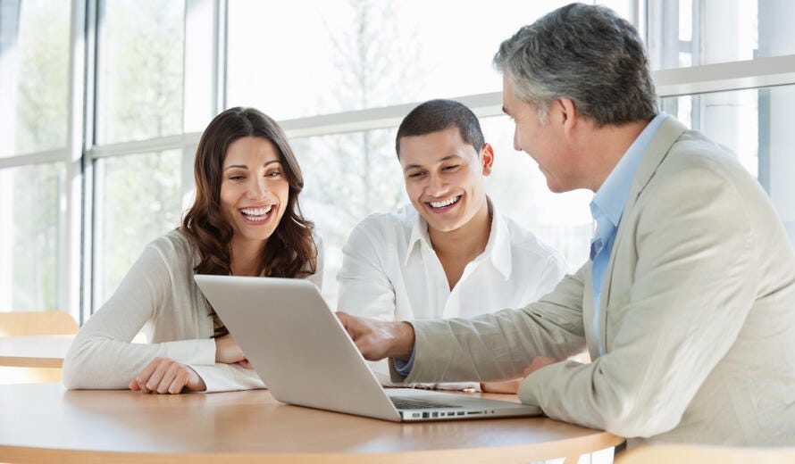 A mature financial consultant advising a happy young couple.