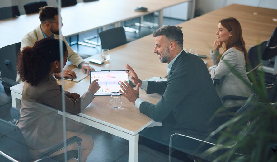 Business team reviews financial data on a tablet.