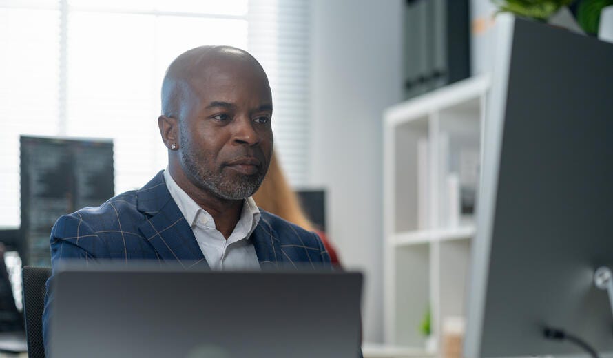 Male employee working at computer discussing strategy.