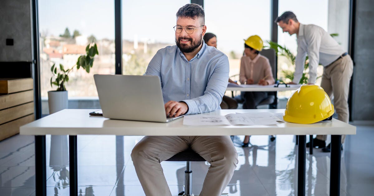 Smiling male engineer using a laptop.