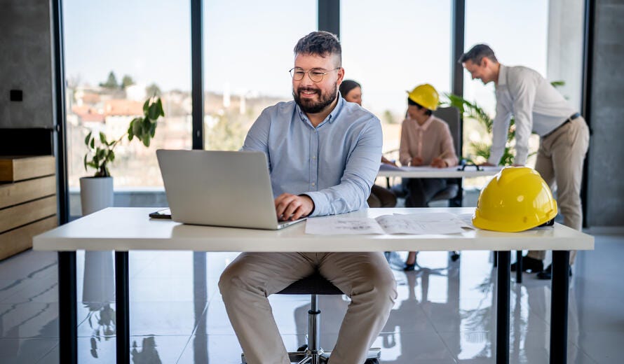 Smiling male engineer using a laptop.