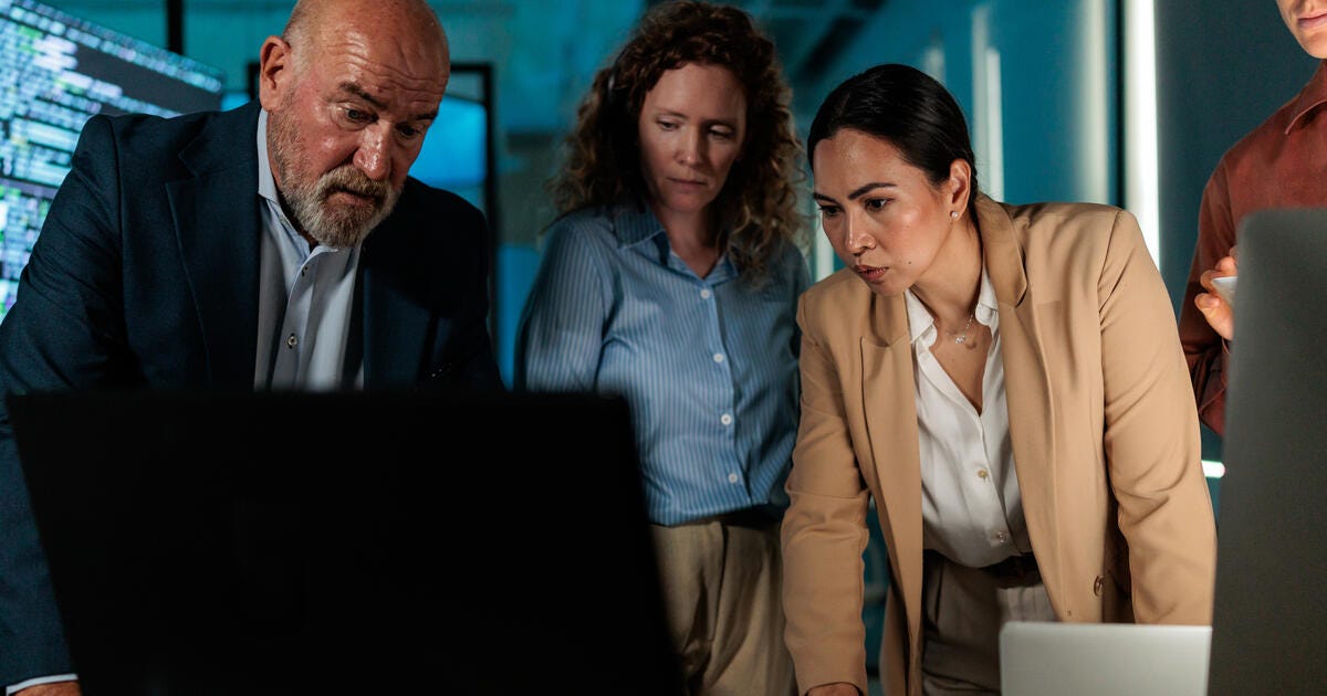 IT professionals gather around a workstation while reviewing system data.